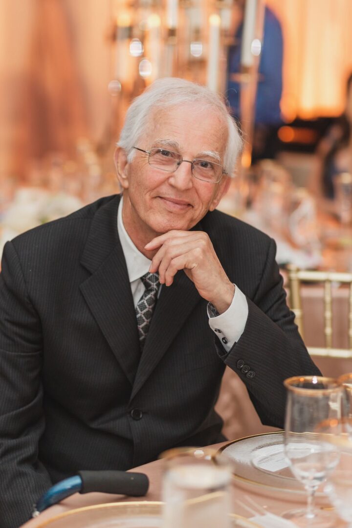 An old man wearing a black suit, smiling at the camera