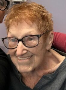 An old man with brown hairs smiling at the camera