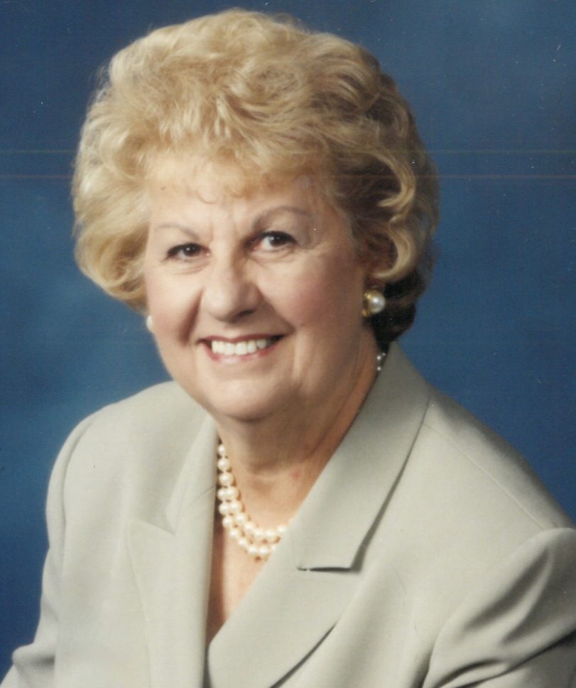 An old woman with brown hairs smiling at the camera