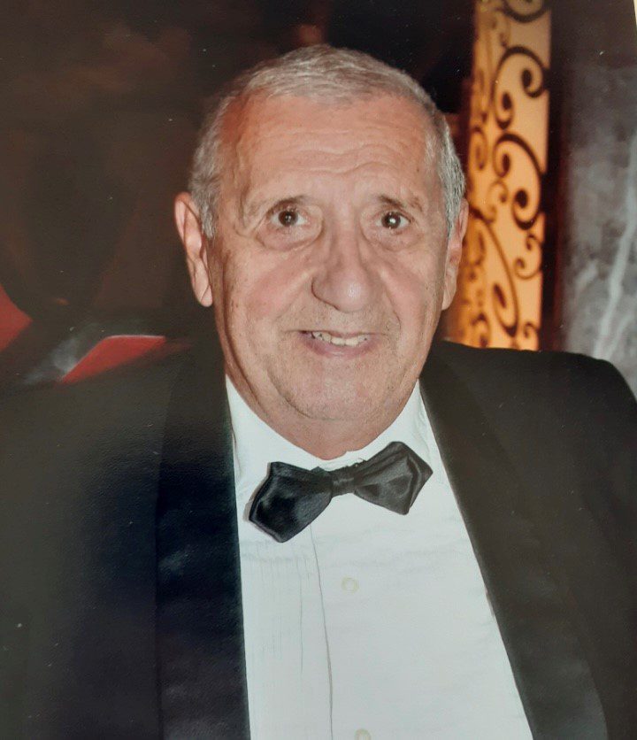 An old man wearing a suit, smiling at the camera