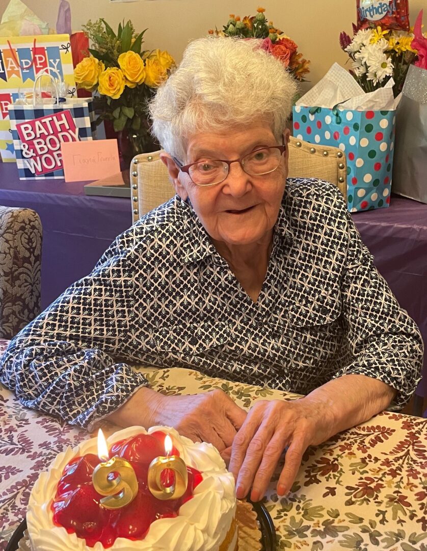An older woman sitting in front of a cake with candles.