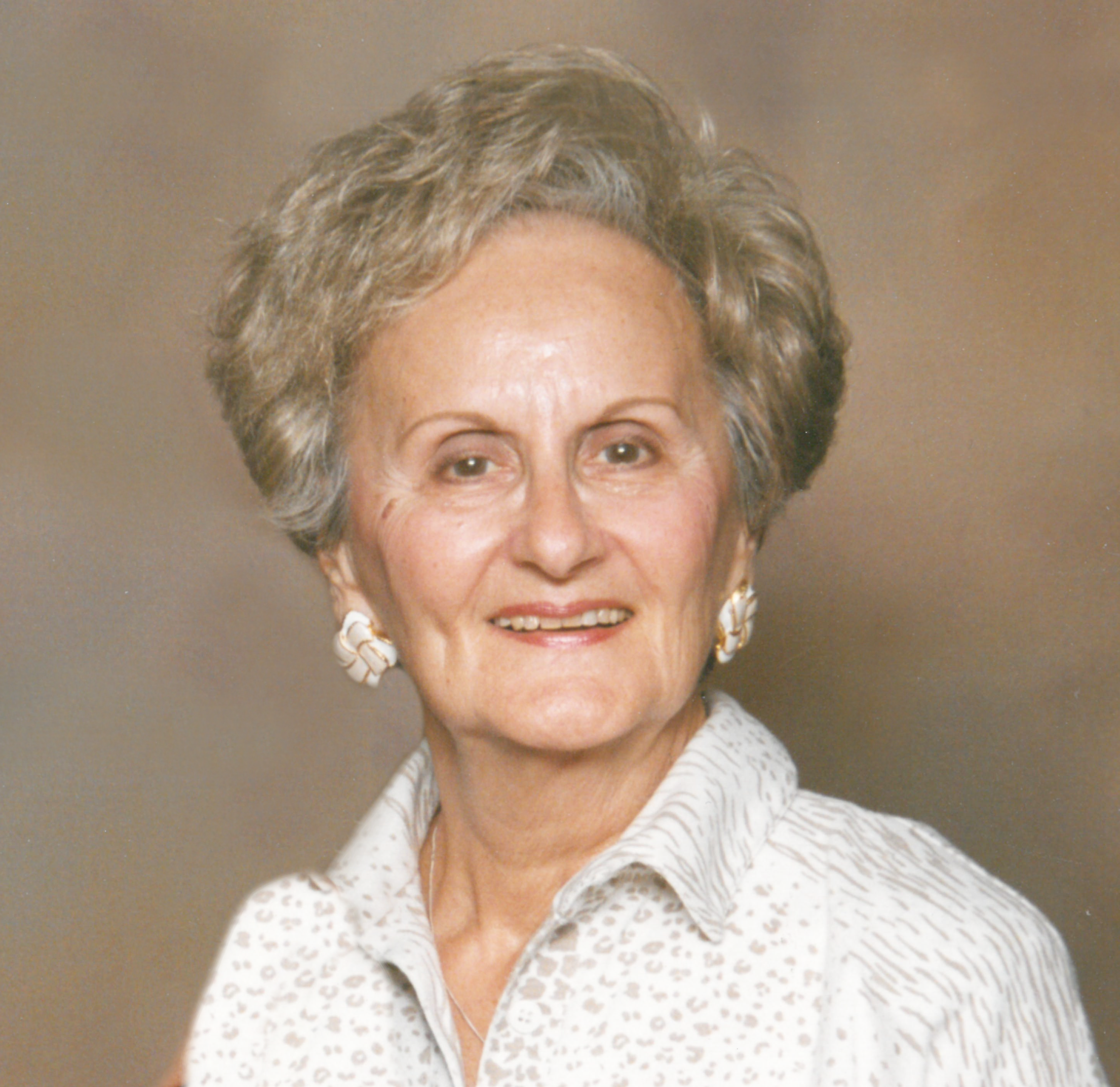 An old lady with brown hairs smiling at the camera