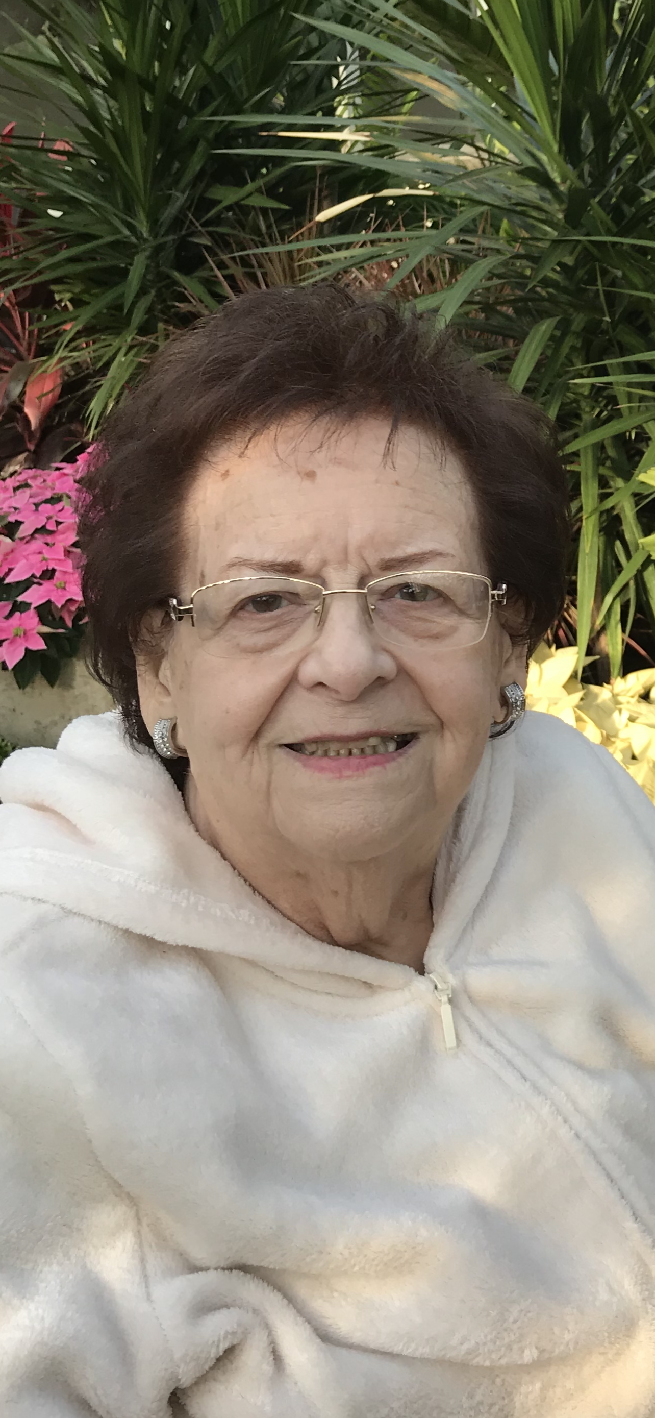 An old woman sitting near trees, smiling at the camera