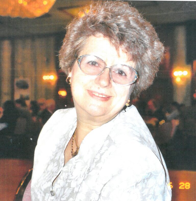 An old woman with curly hairs smiling at the camera