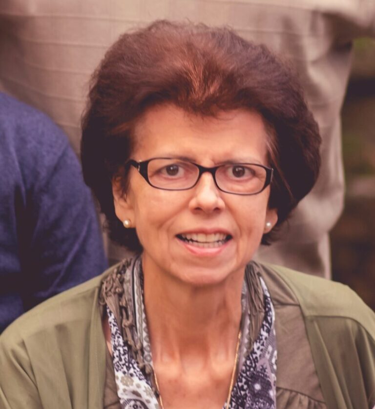A woman in glasses is smiling for the camera.