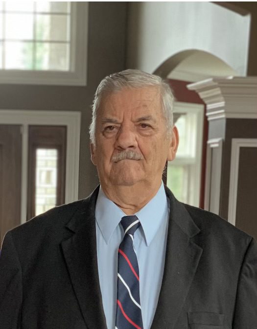 A man in a suit and tie standing in front of a house.