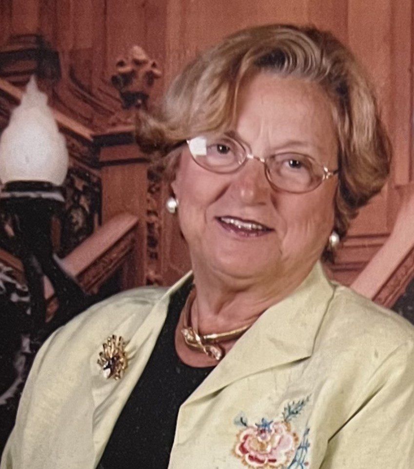 An older woman wearing glasses and a jacket.