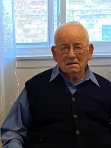 An older man sitting in front of a window.