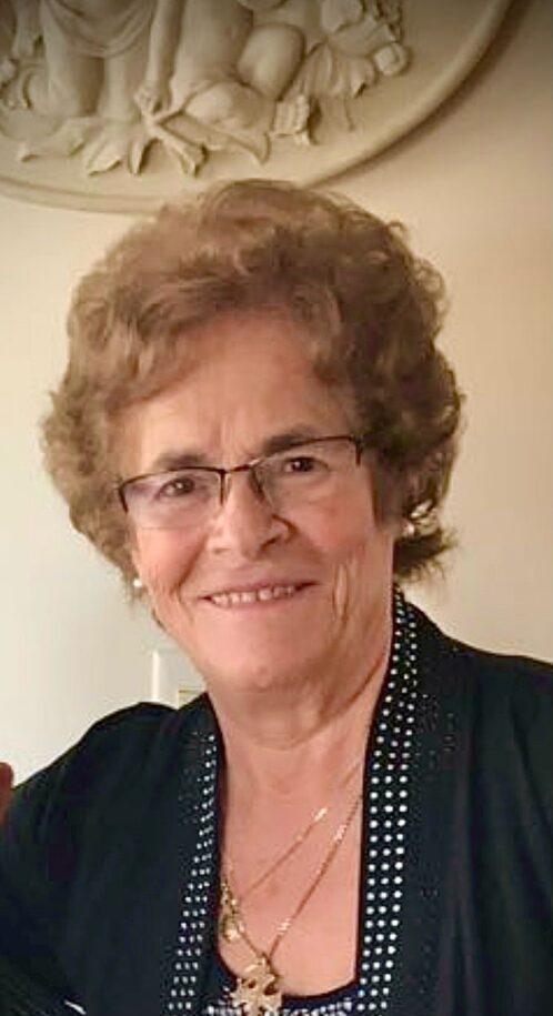 An older woman with glasses is smiling for the camera.