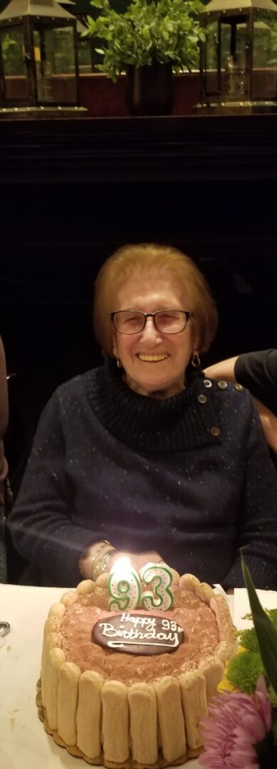 A woman sitting at a table with a birthday cake.