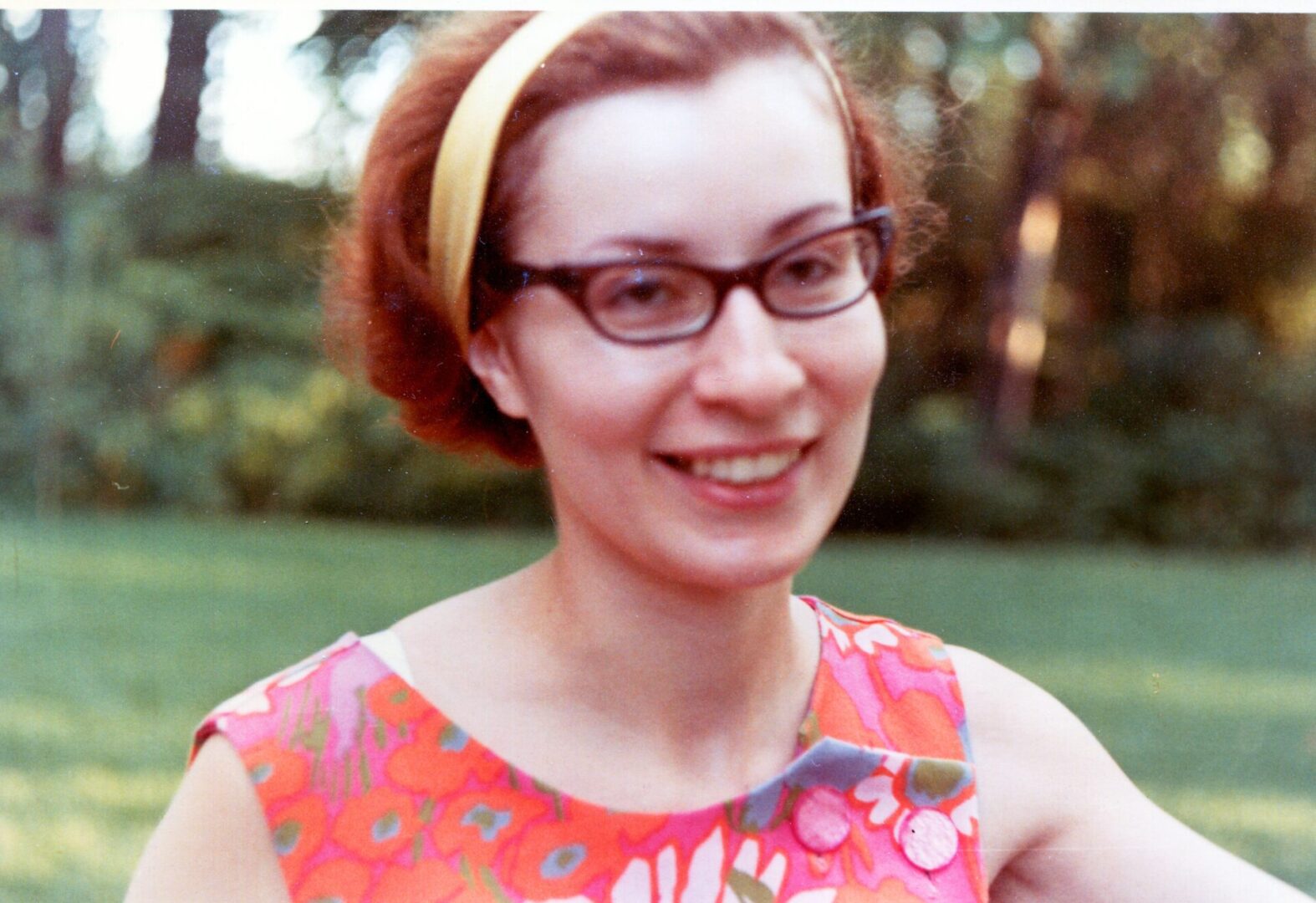 A woman wearing glasses and a floral dress.