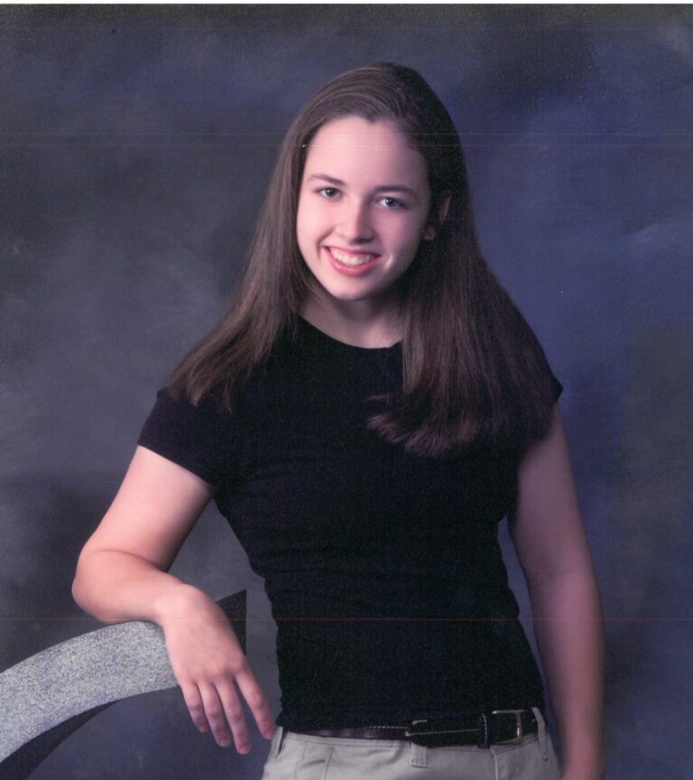 A smiling young woman with long hair posing for a portrait.