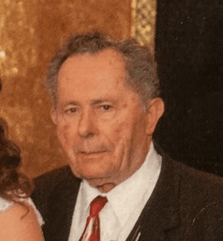 A mature man in a suit and tie with a solemn expression.