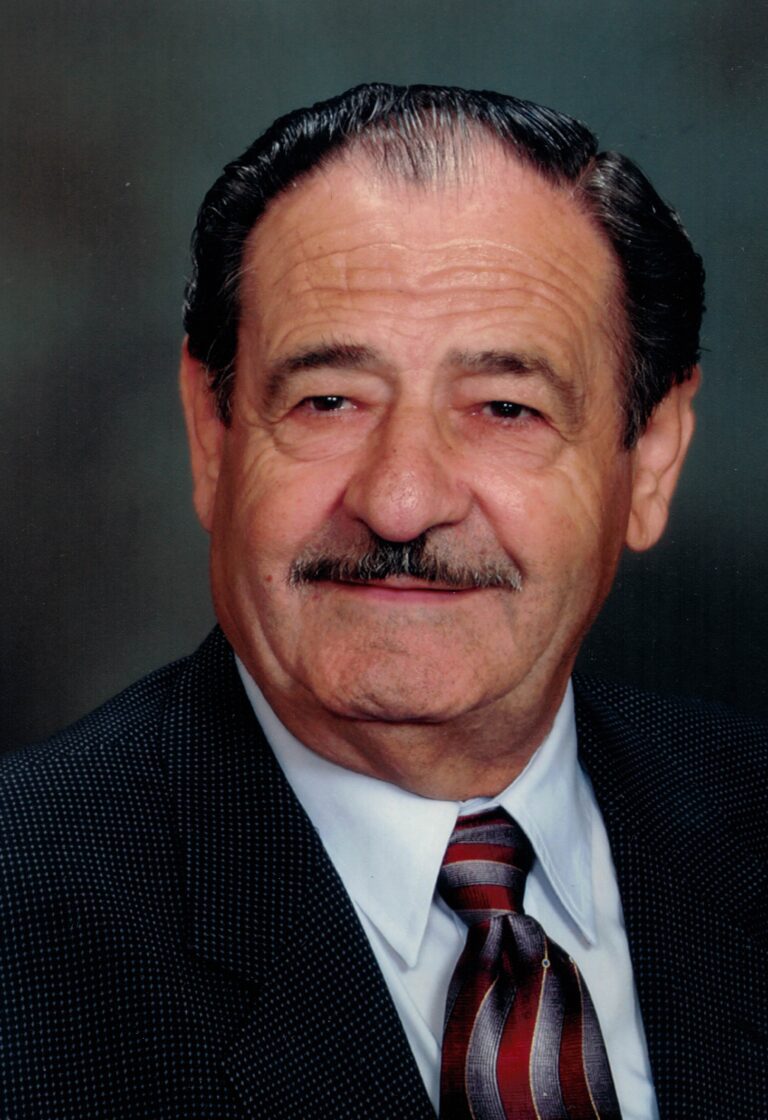 A portrait of an elderly man with a mustache, smiling at the camera.