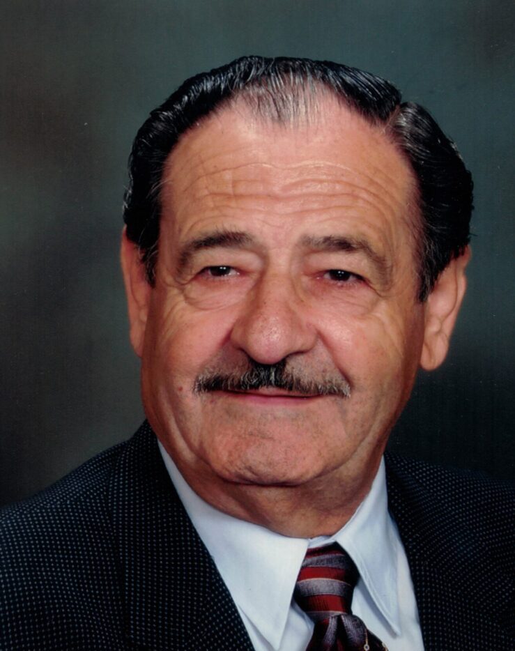 A portrait of an elderly man with a mustache, smiling at the camera.