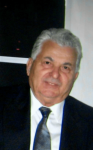 An older gentleman with gray hair wearing a suit and tie smiling at the camera.