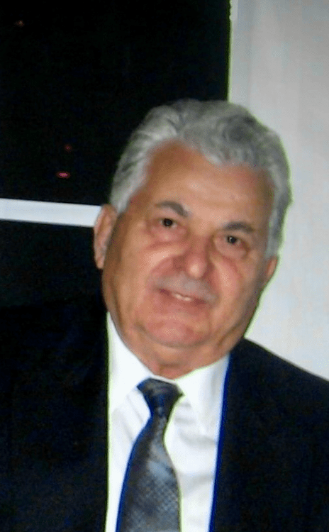 An older gentleman with gray hair wearing a suit and tie smiling at the camera.
