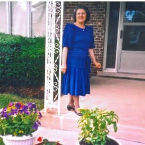 Woman in blue dress standing by door.