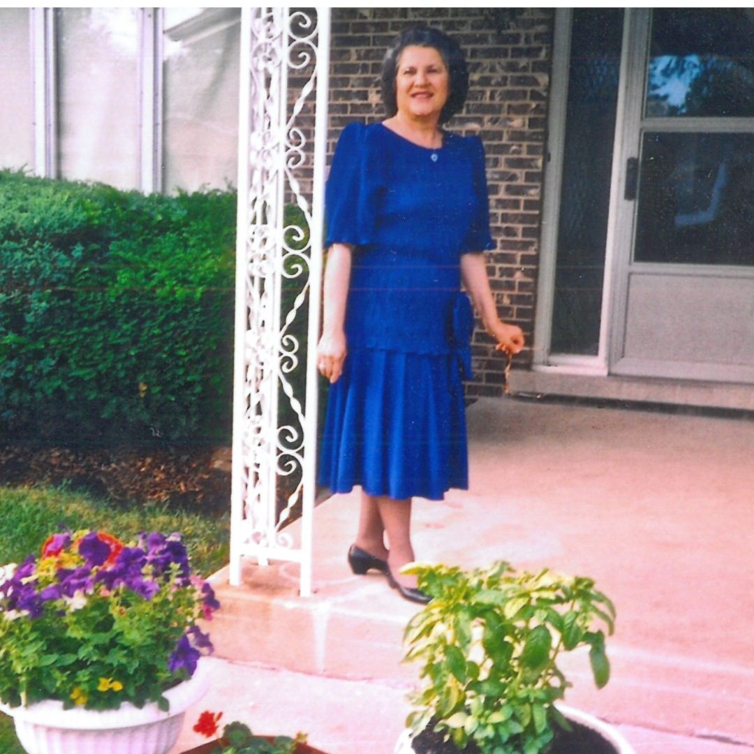 Woman in blue dress standing by door.
