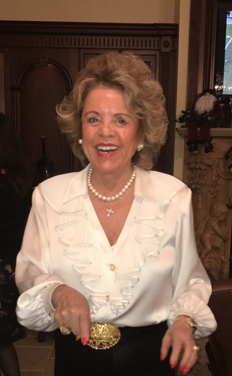 Smiling woman in a white blouse with a pearl necklace.